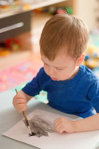 Portrait of a boy with blond hair, painting a picture. early childbirth. creativity since childhood