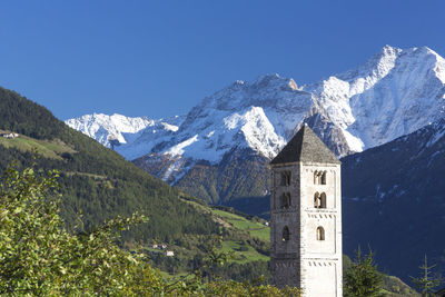 Built structure by snowcapped mountains against sky