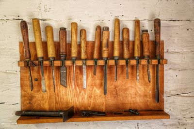 Close-up of chisels arranged on wooden shelf