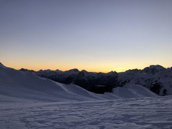 Scenic view of snow covered mountains against sky during sunset