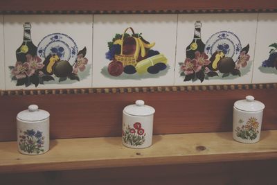 Tea light painting on shelf against wall