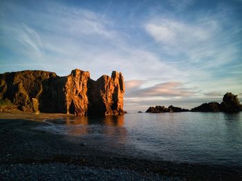 Rock formation by sea against sky