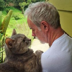 Close-up of senior man and cat looking at each other