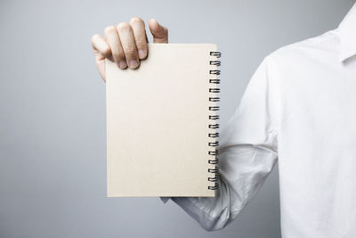 Close-up of hand holding book against white background