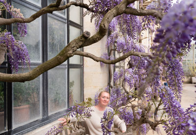 Beautiful middle-aged woman sits on a bench in the thickets of blooming wisteria