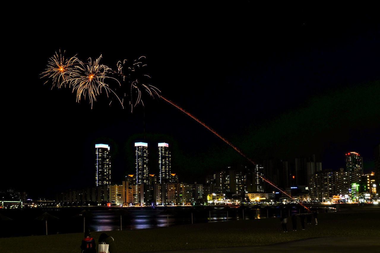 LOW ANGLE VIEW OF FIREWORK DISPLAY OVER BUILDINGS AGAINST SKY