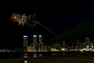 Low angle view of firework display in city against sky at night