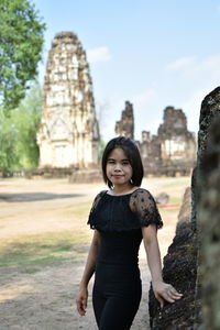 Portrait of young woman standing against old ruin temple