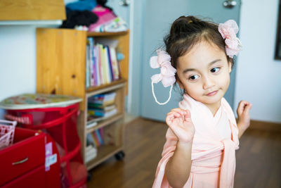 A little girl is standing in a beautiful dress with hair accessories. pretend play at home.