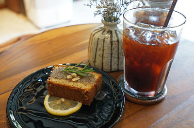Close up lemon and poppy seed cake served with iced black coffee