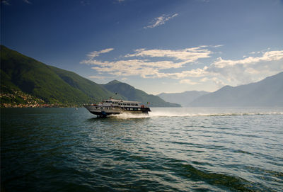 Boat sailing on sea against mountains