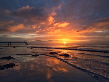 Scenic view of sea against dramatic sky during sunset