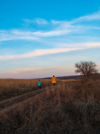 Travelers father daughter walking together on hill scenic landscape sunset sky hiking trail journey