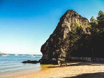 Rock formation on beach against clear blue sky