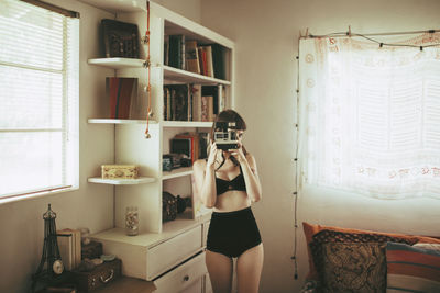 Woman photographing while standing at home