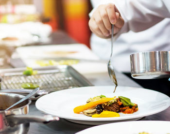 Midsection of person preparing food in restaurant