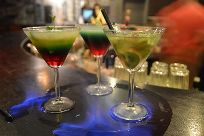 Close-up of cocktails in martini glasses on burning bar counter
