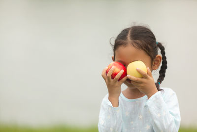 Portrait of a girl holding apple against white background