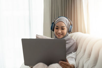 Portrait of young woman using laptop at home