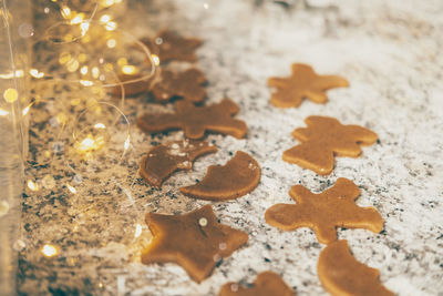 Making christmas cookies. figured gingerbread cookies on the kitchen table with holiday lights