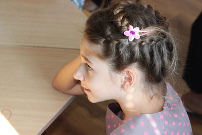 Side view of girl with braided hair leaning on table