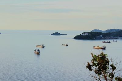 Boats sailing in sea against sky during sunset