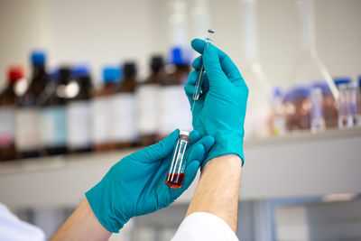 Cropped hand of scientist holding vial and syringe in laboratory