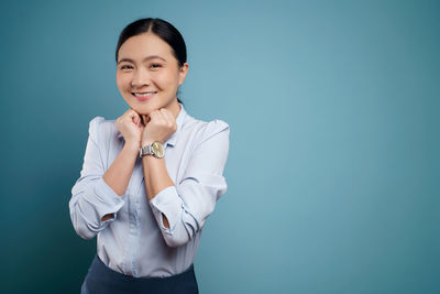 Portrait of a smiling young woman against blue background