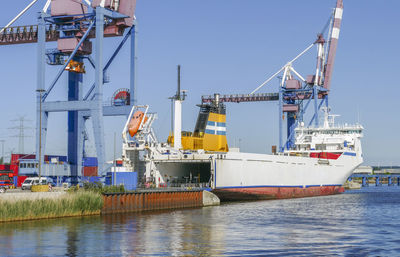 Cranes at harbor against clear sky