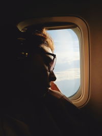 Close-up of young woman sleeping by window in airplane