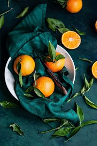 Orange fruits in the tray with a knife and leaves of orange fruit.