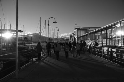 People on sidewalk in city against sky