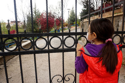 Rear view of girl standing by railing