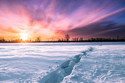 Scenic view of frozen lake against sky during sunset