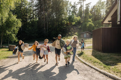 Happy kids running with counselors on footpath at summer camp