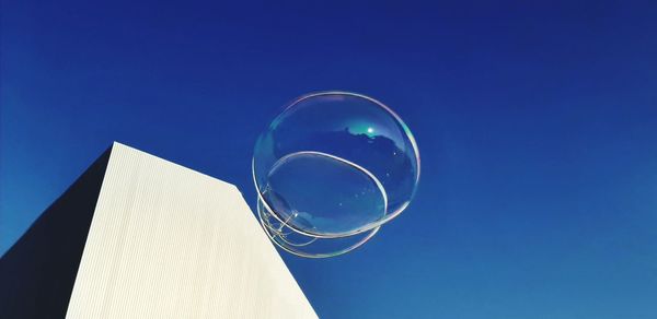 Low angle view of bubbles against blue sky