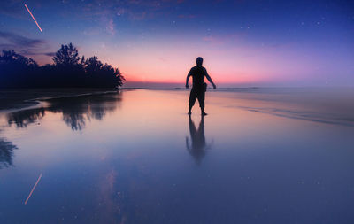 Silhouette man standing at beach against sky during sunset