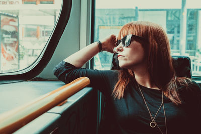 Woman looking through window while sitting in train