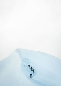 People on snowcapped mountain against clear sky