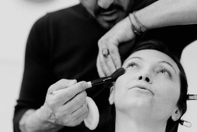 Midsection of man applying make-up for woman 