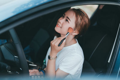 Woman applying make-up in car