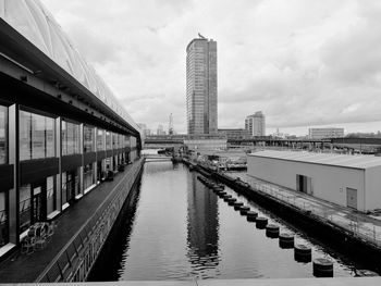 Bridge over river by buildings against sky