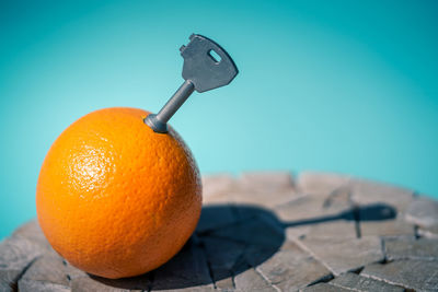 An orange fruit on a wooden table with a key inside pulp. blue background