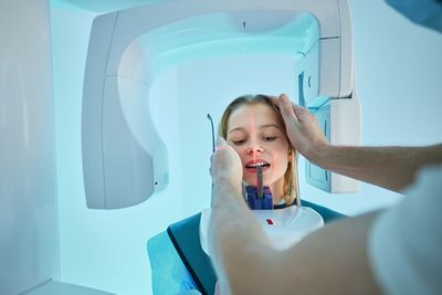 High angle view of dentist scanning girls face at clinic