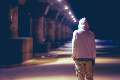 Rear view of man standing on illuminated lamp