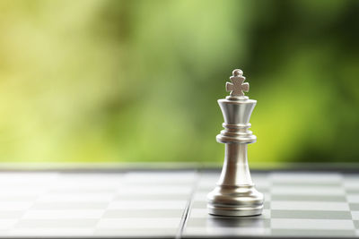 Close-up of king on chess board against plants
