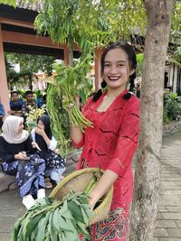 Portrait of smiling young woman picking plants