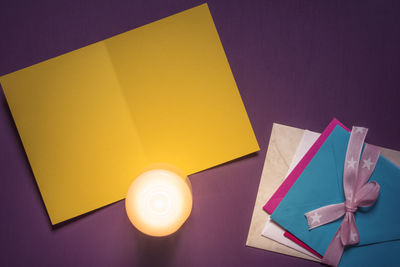 Directly above shot of yellow paper by greeting cards on table