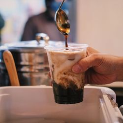 Close-up of hand pouring drink in glass