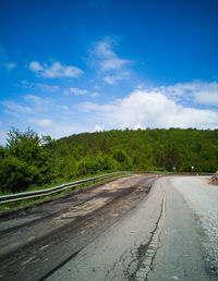 Road by trees against sky